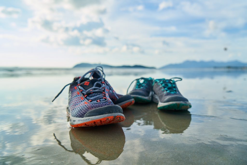 Two pairs of running shoes on a wet sandy beach